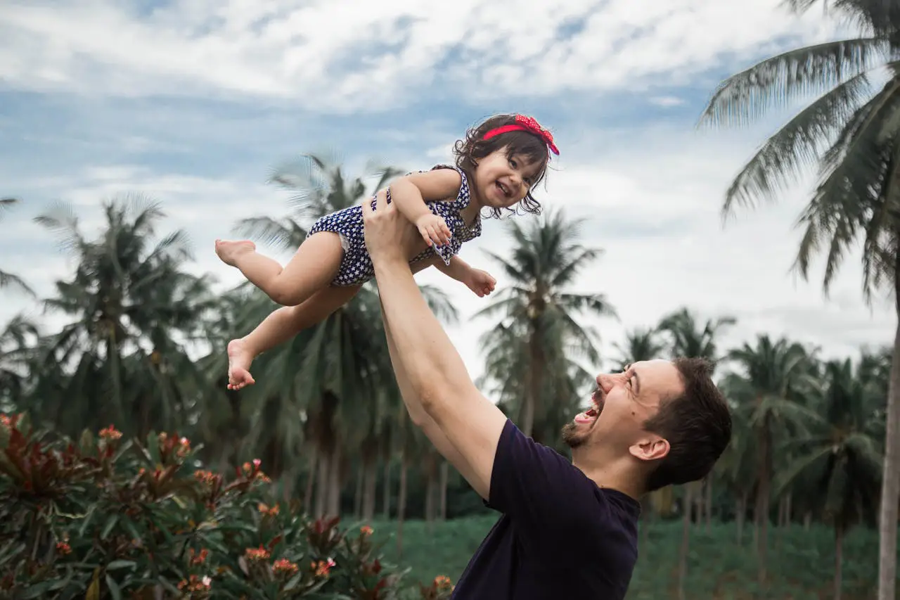 A man joyfully holds a baby in the air